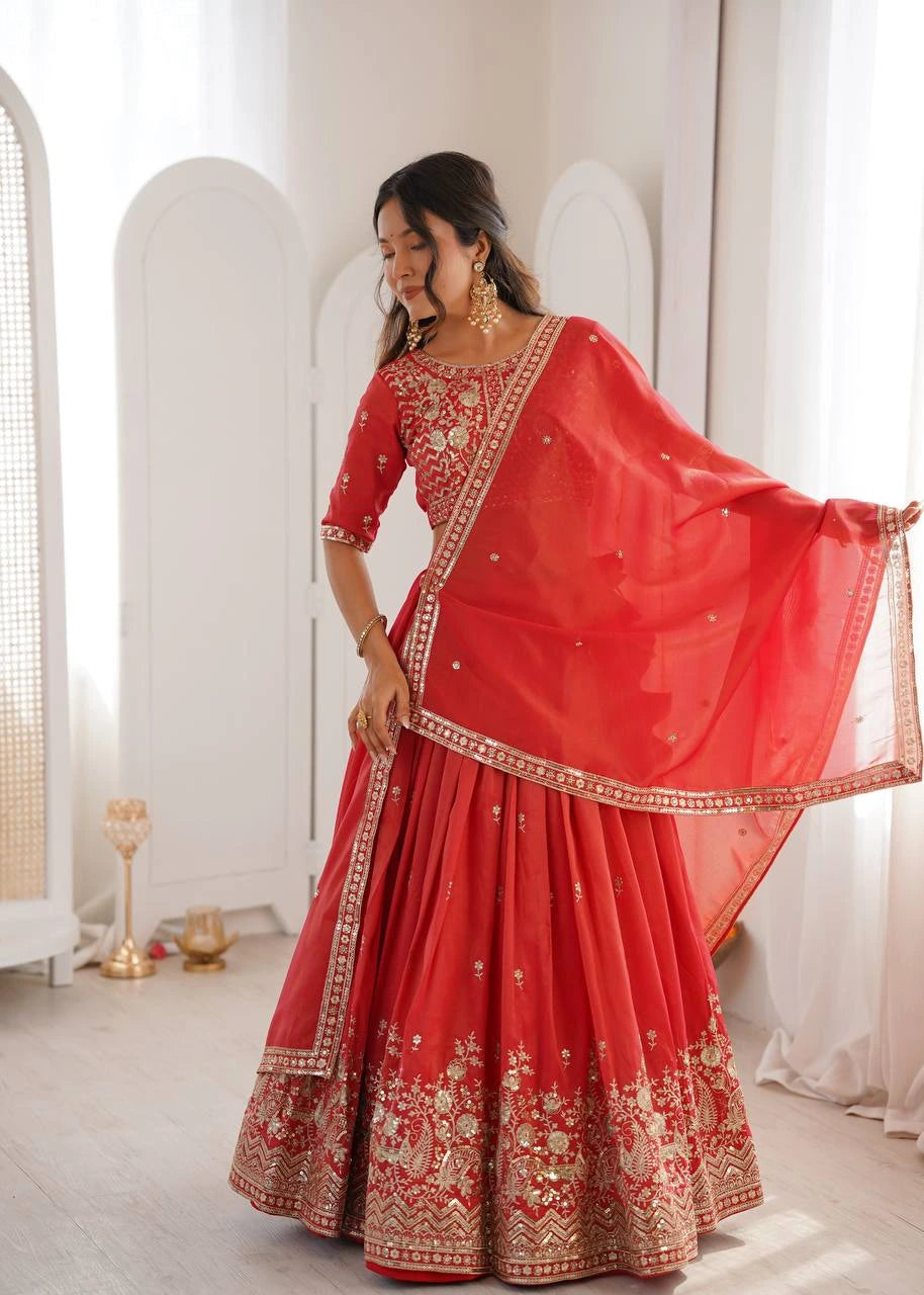 Woman in a red traditional outfit with gold embroidery in a minimalistic room.