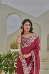 Woman in a maroon saree with white embroidery standing outdoors.