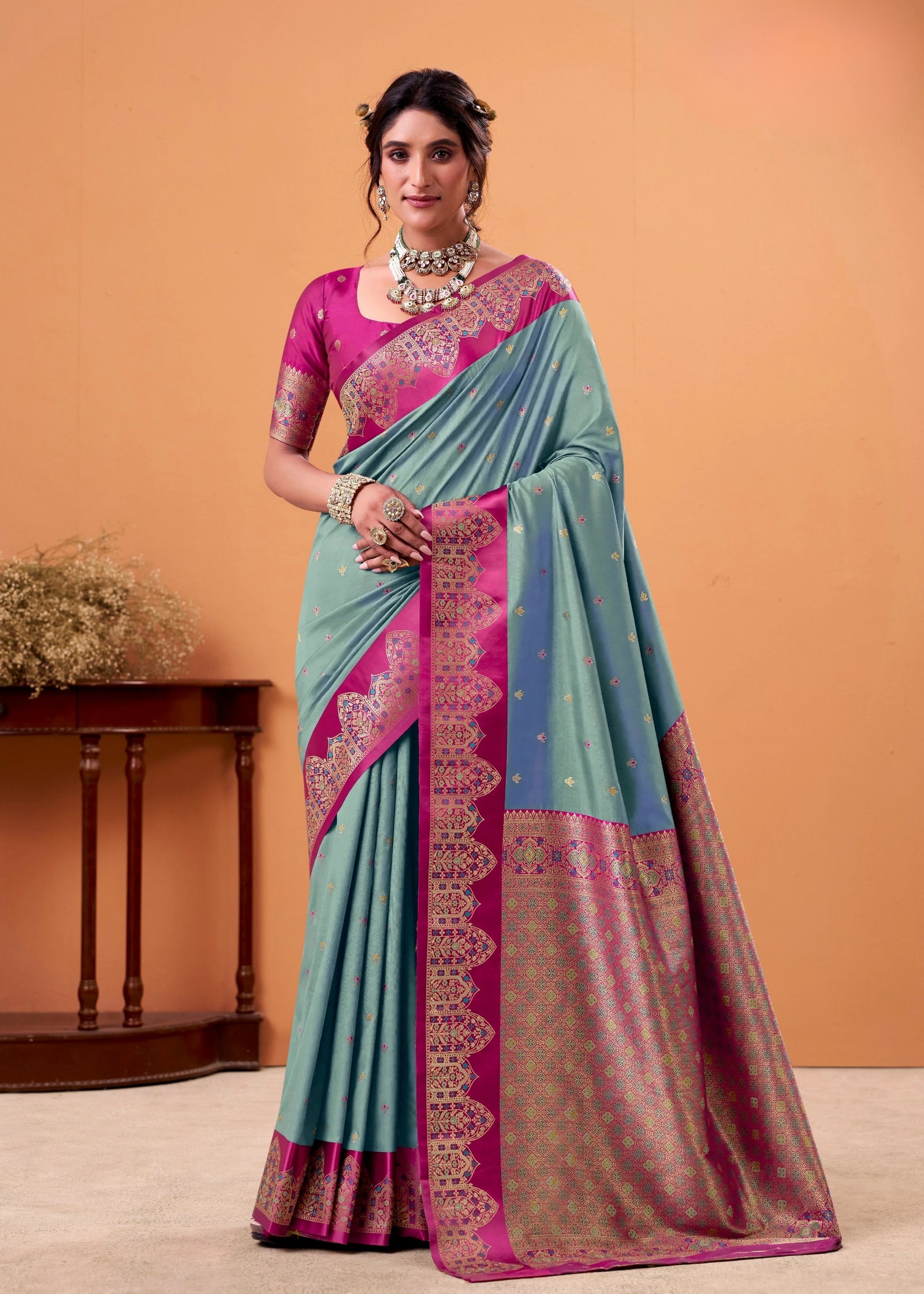 Woman wearing a traditional saree with a pink blouse against an orange background