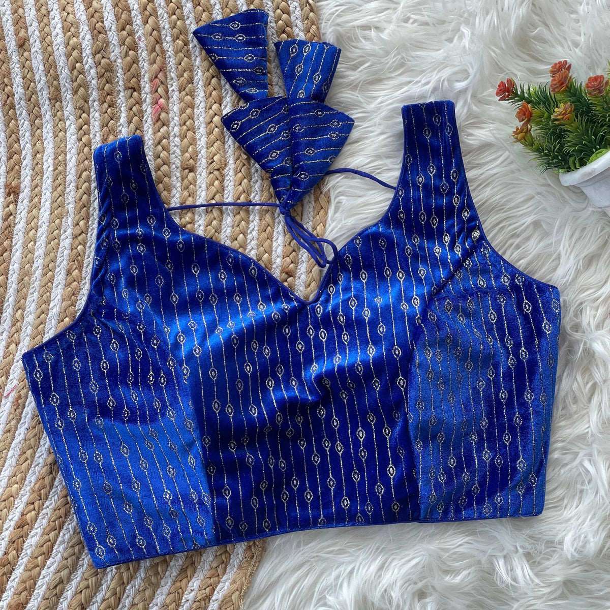 Blue patterned top on a textured surface with a small plant in the corner