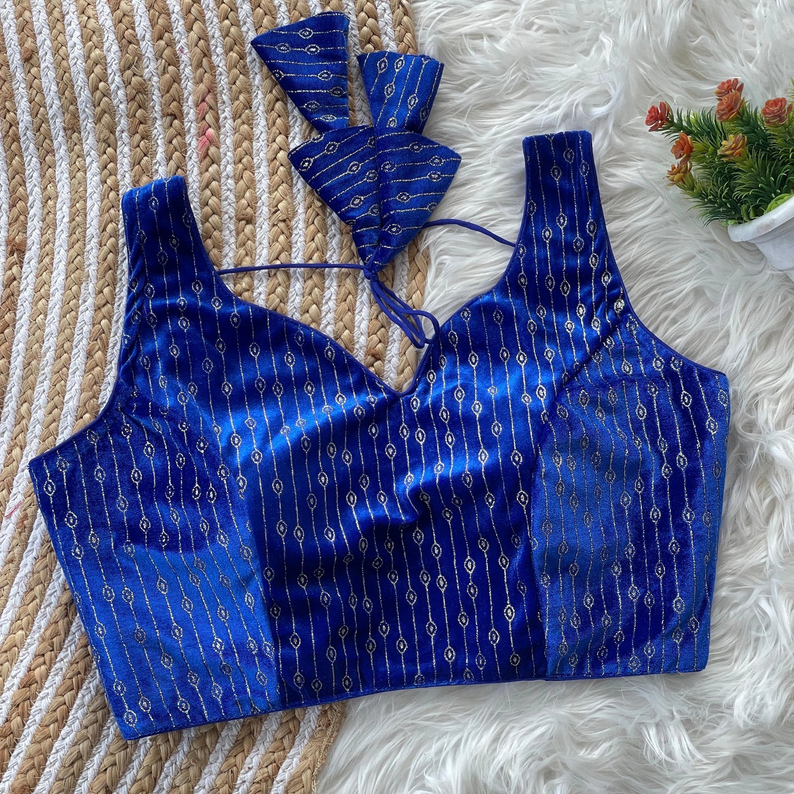 Blue patterned top on a textured surface with a small plant in the corner