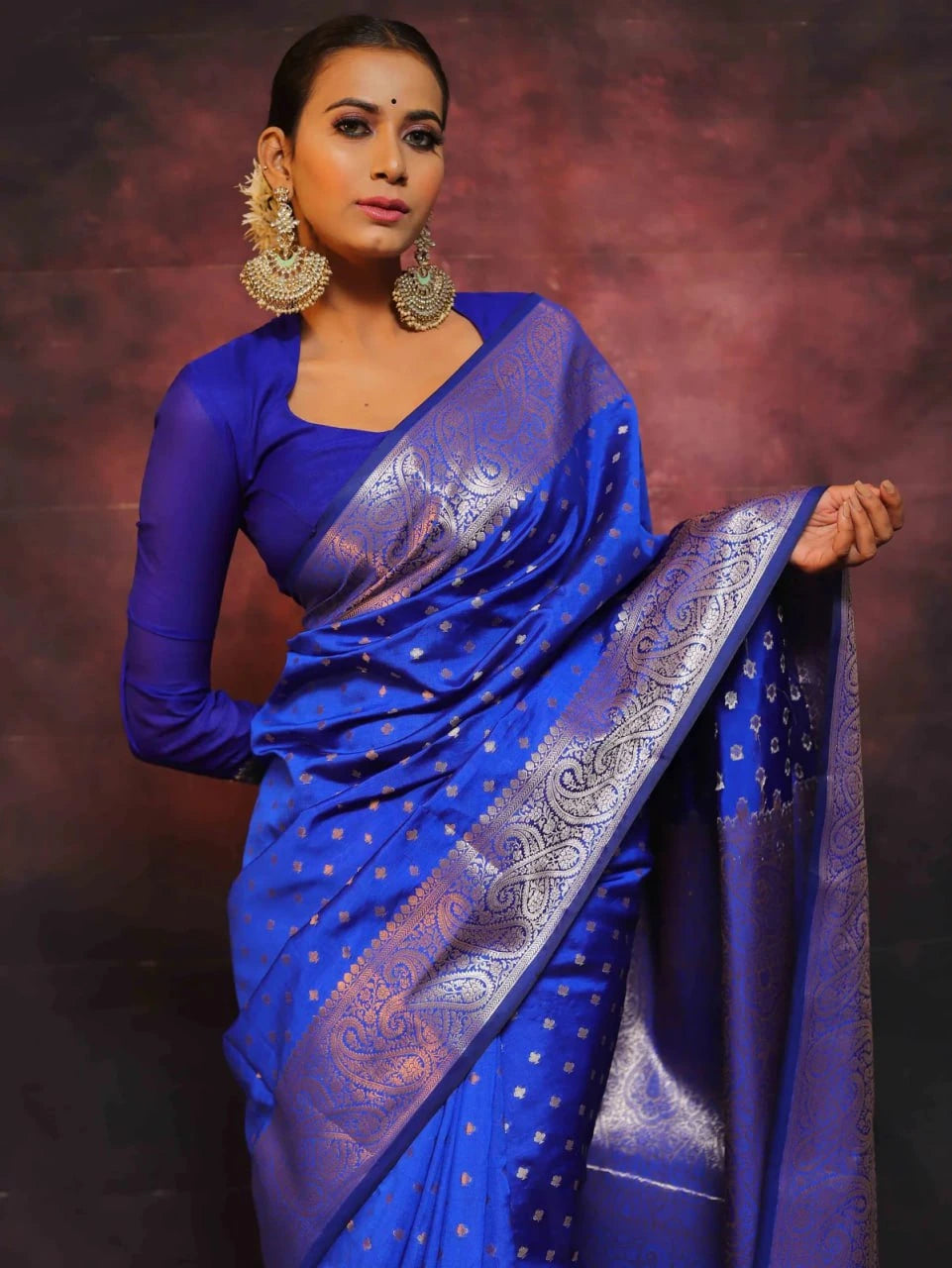 Woman wearing a blue saree with a patterned border against a dark background