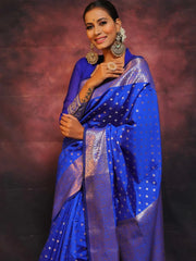 Woman wearing a blue saree with a patterned border against a dark background