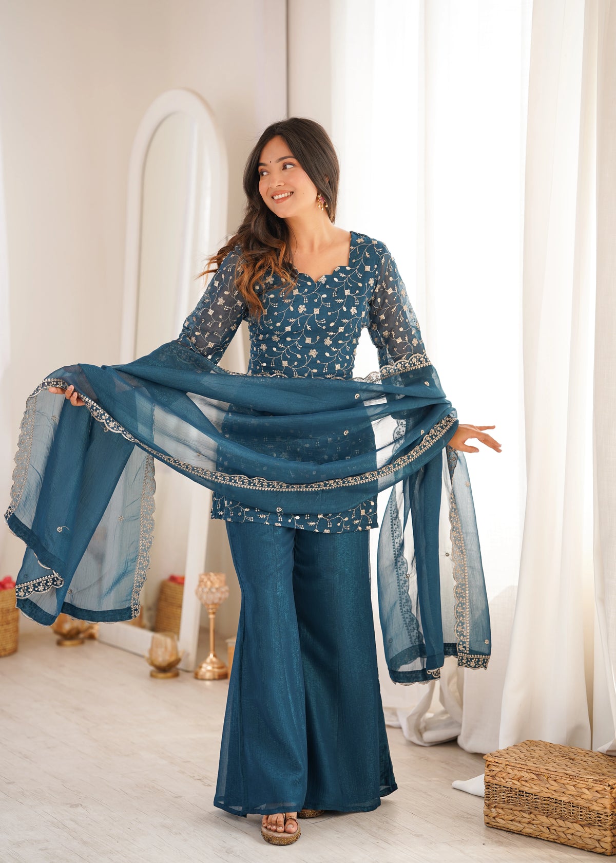 Woman in a blue traditional outfit with a matching scarf in a bright room.