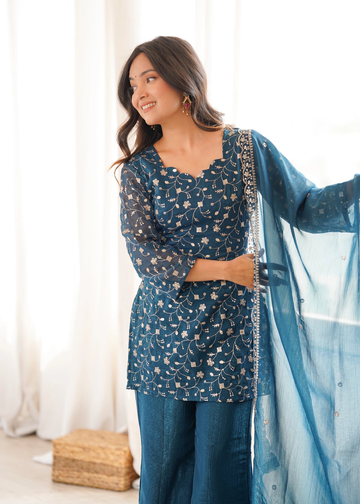 Woman in a blue traditional outfit with a matching dupatta, standing indoors.