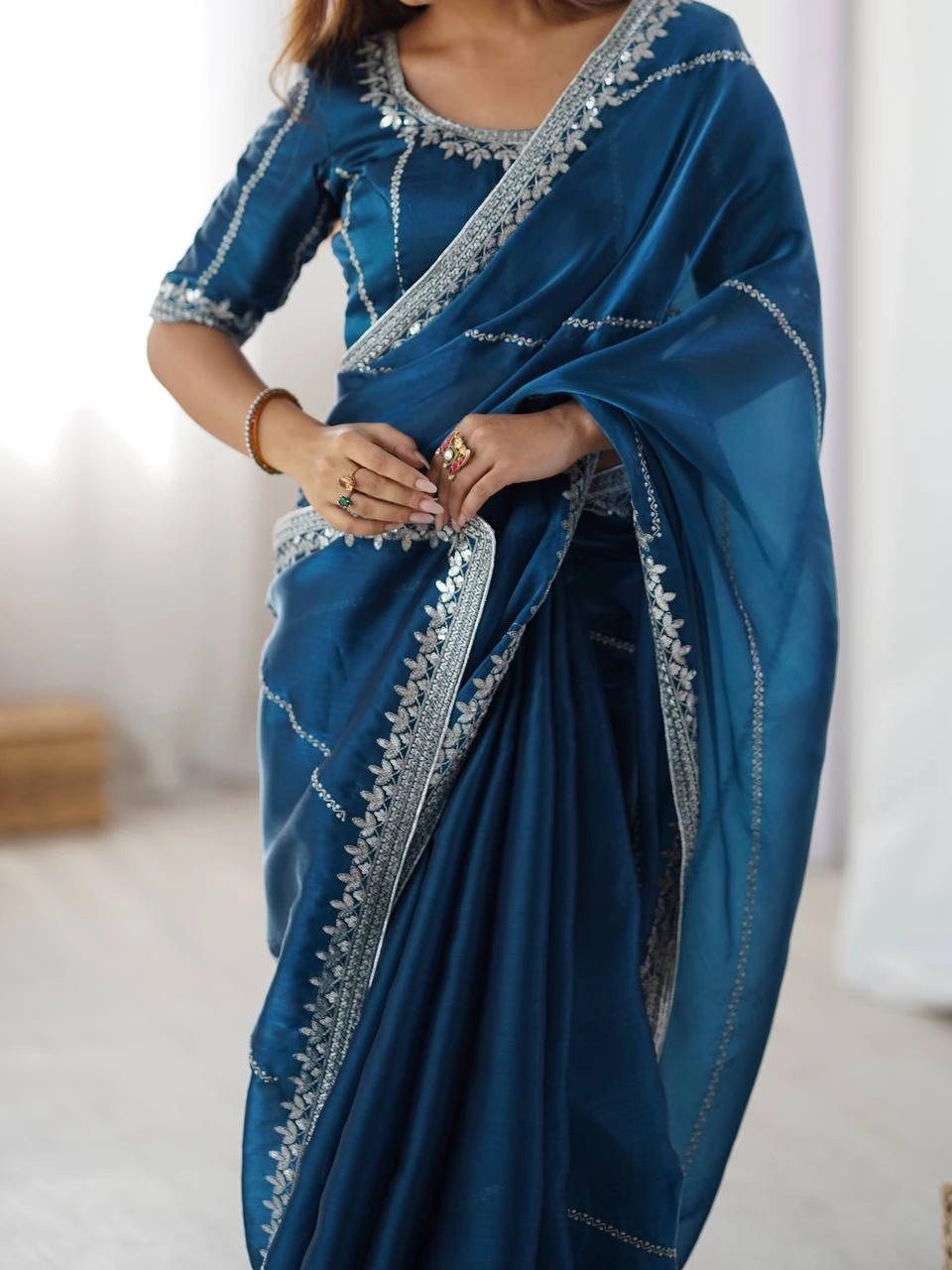 Blue saree with silver border worn by a person, against a neutral background