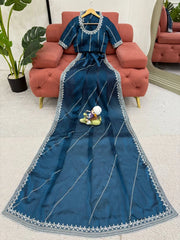 Blue saree with silver border on a hanger against a living room background
