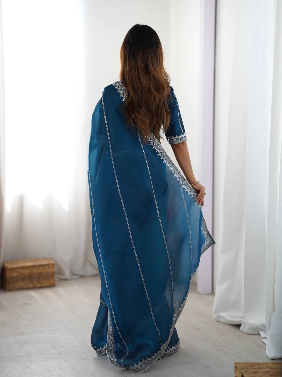 Woman wearing a blue saree with white patterns in a minimalistic setting