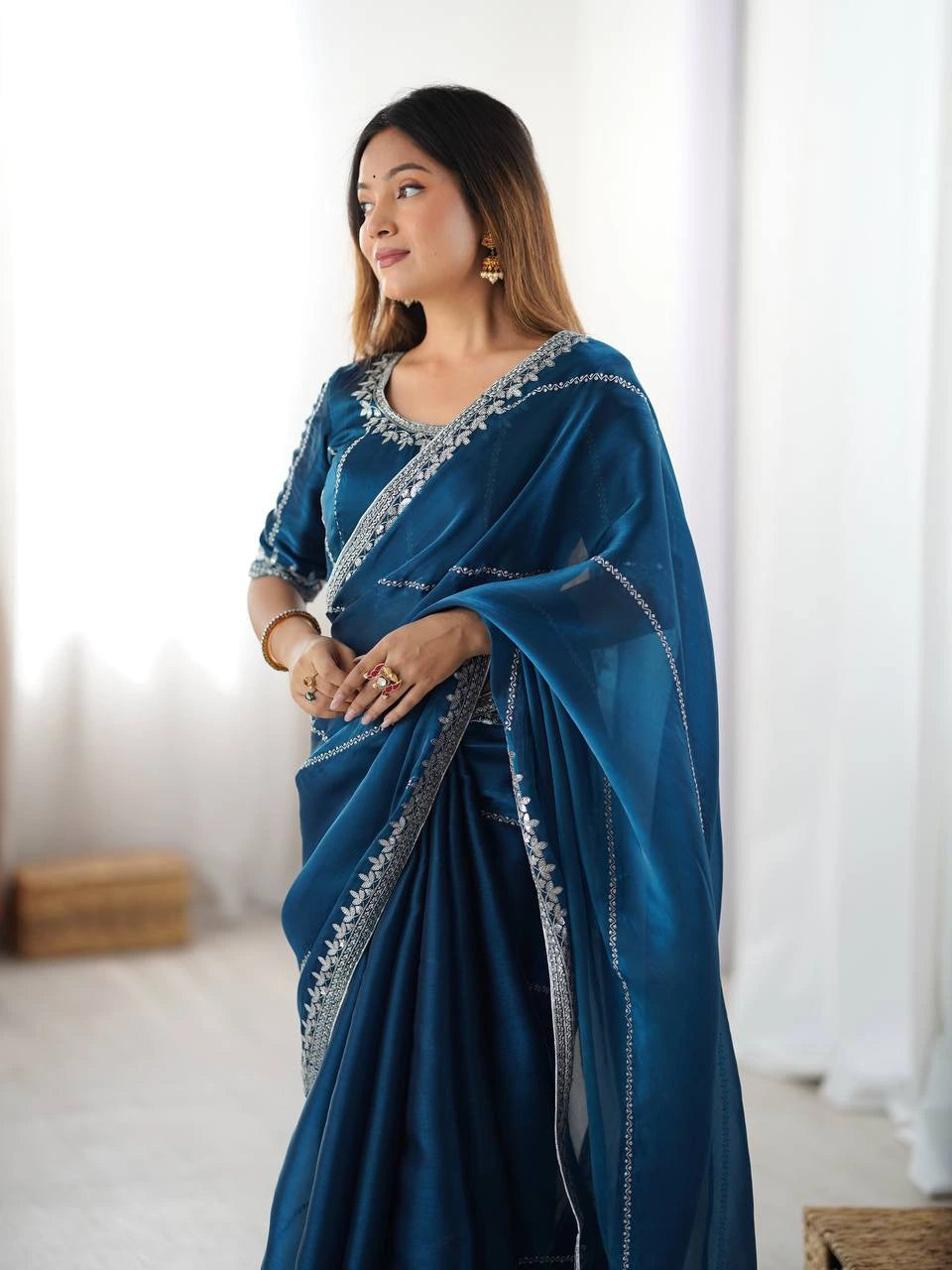 Woman wearing a blue saree with silver border indoors