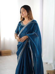 Woman wearing a blue saree with silver border indoors