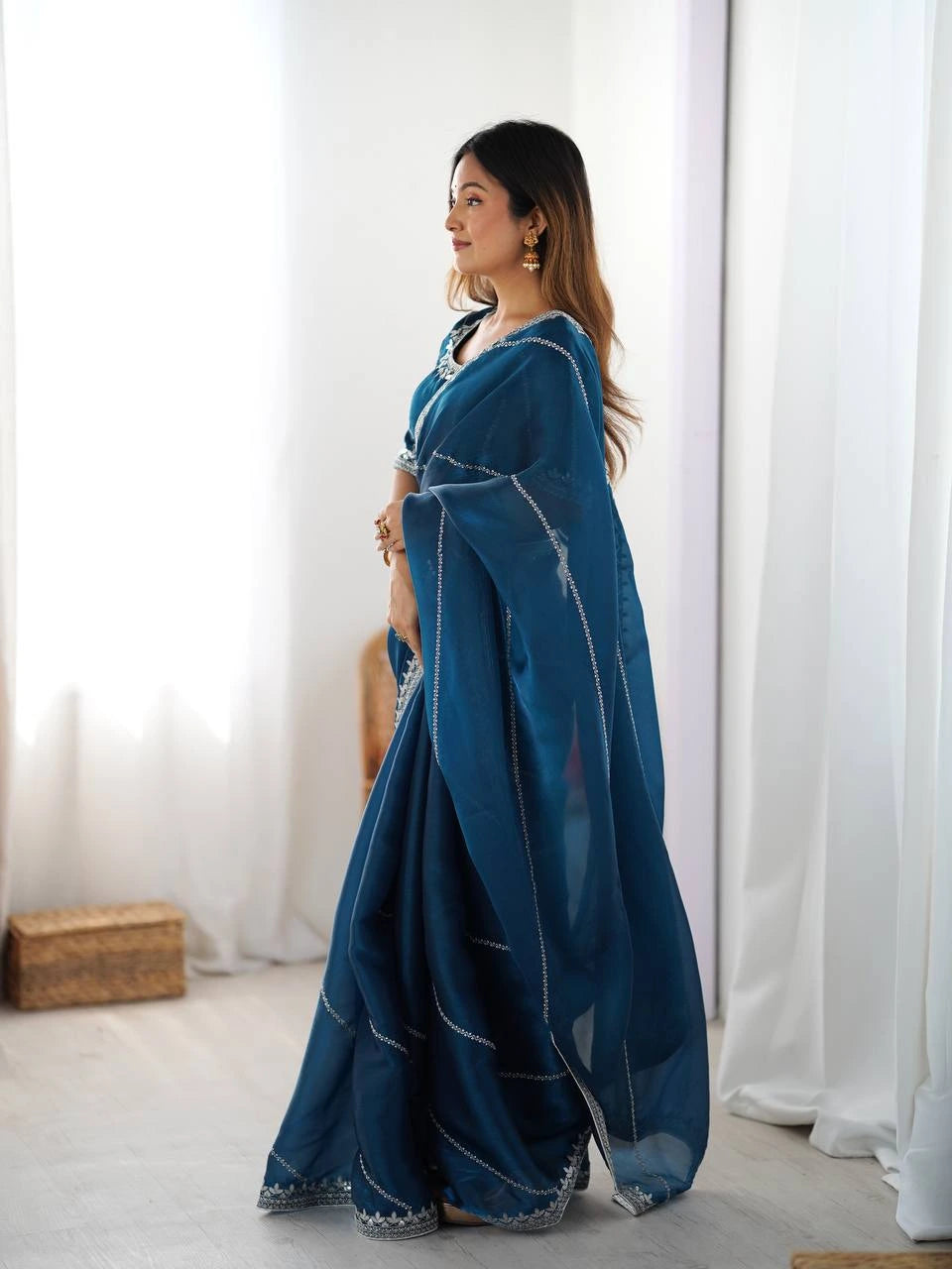 Woman wearing a blue saree with white patterns in a minimalistic setting