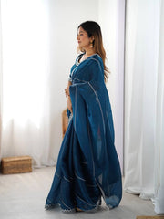 Woman wearing a blue saree with white patterns in a minimalistic setting
