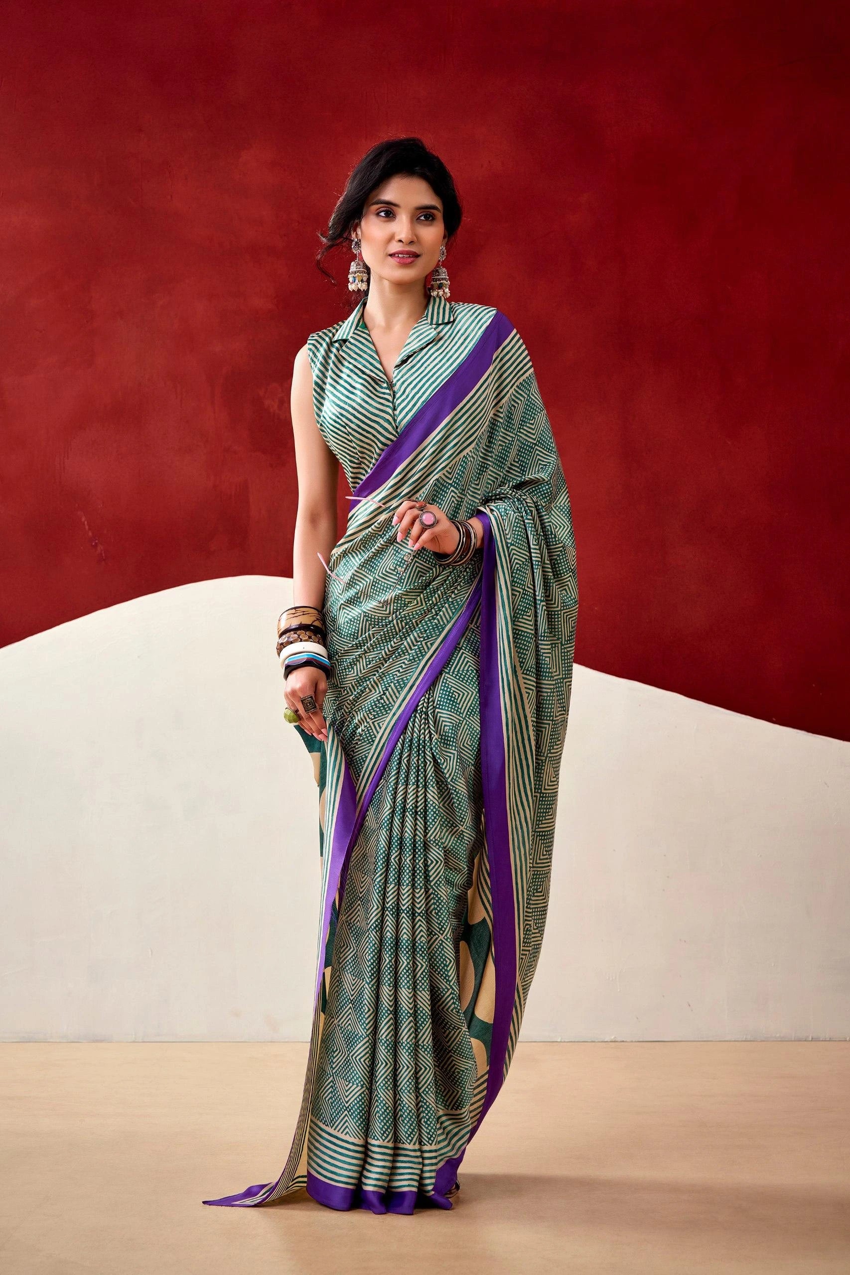 Woman wearing a green and purple saree against a red and beige background