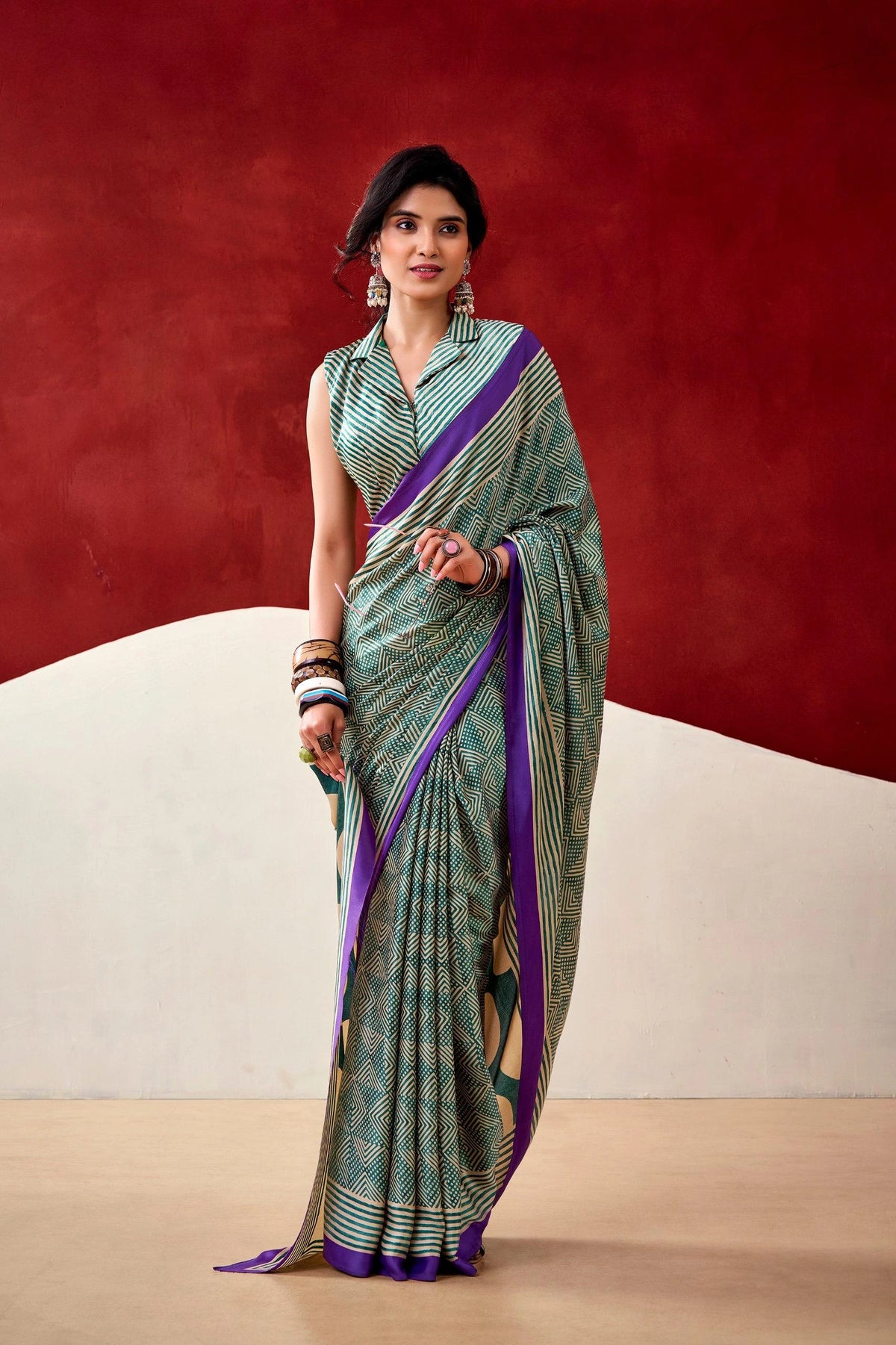 Woman wearing a green and purple saree against a red and beige background
