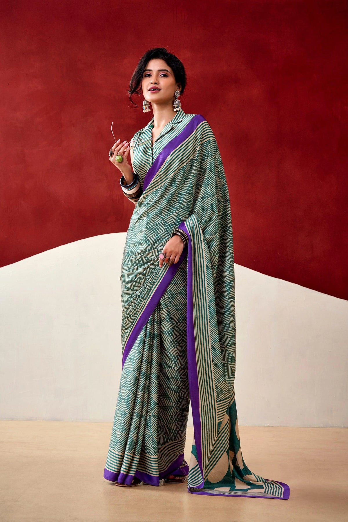 Woman wearing a green and purple saree with a red and beige background