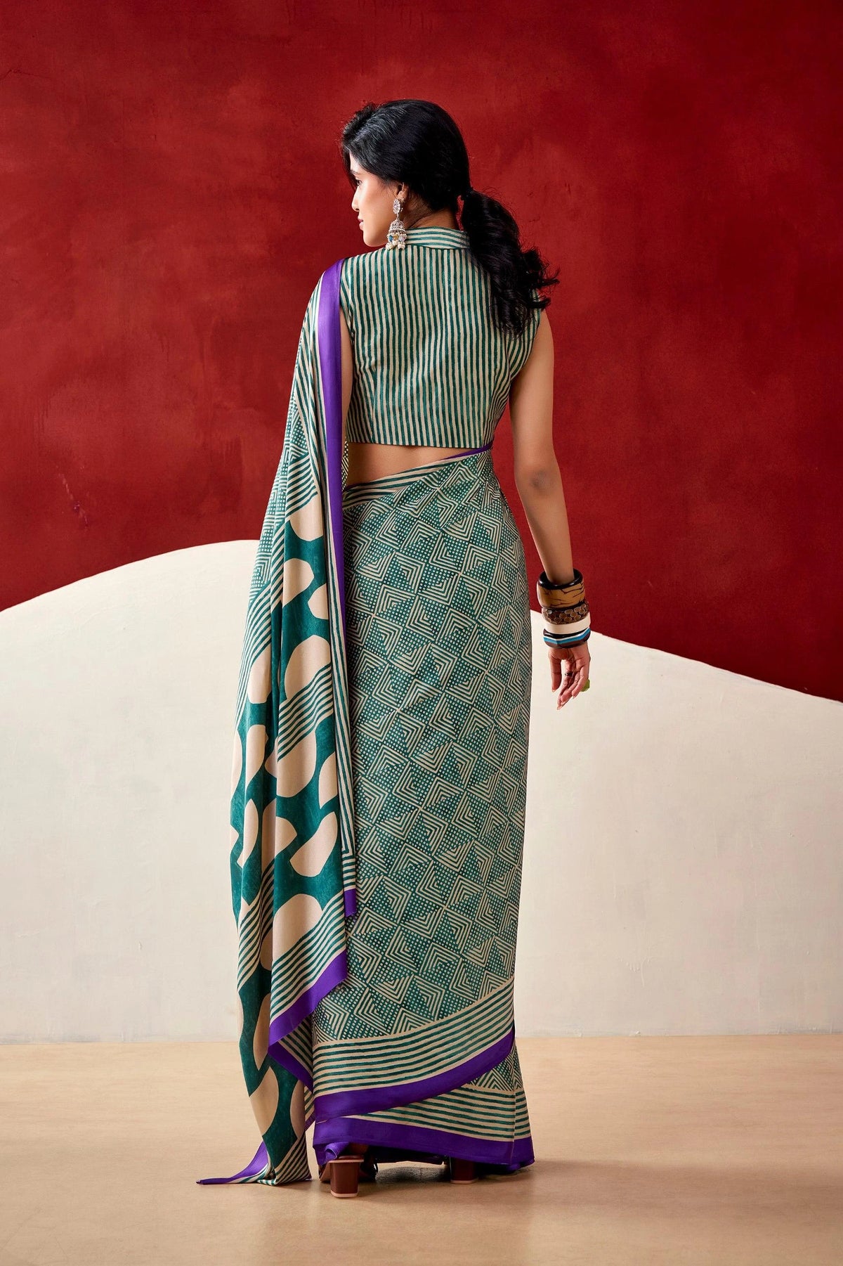 Woman wearing a green and purple saree with a red background