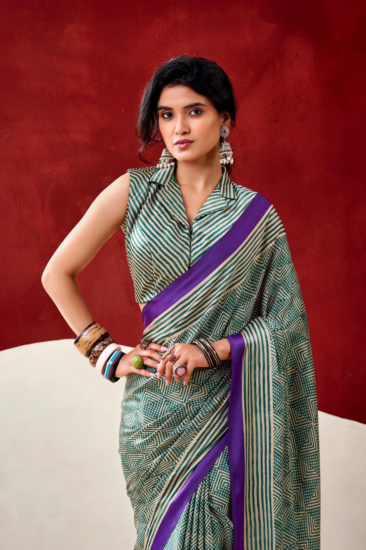 Woman wearing a green and purple saree against a red background