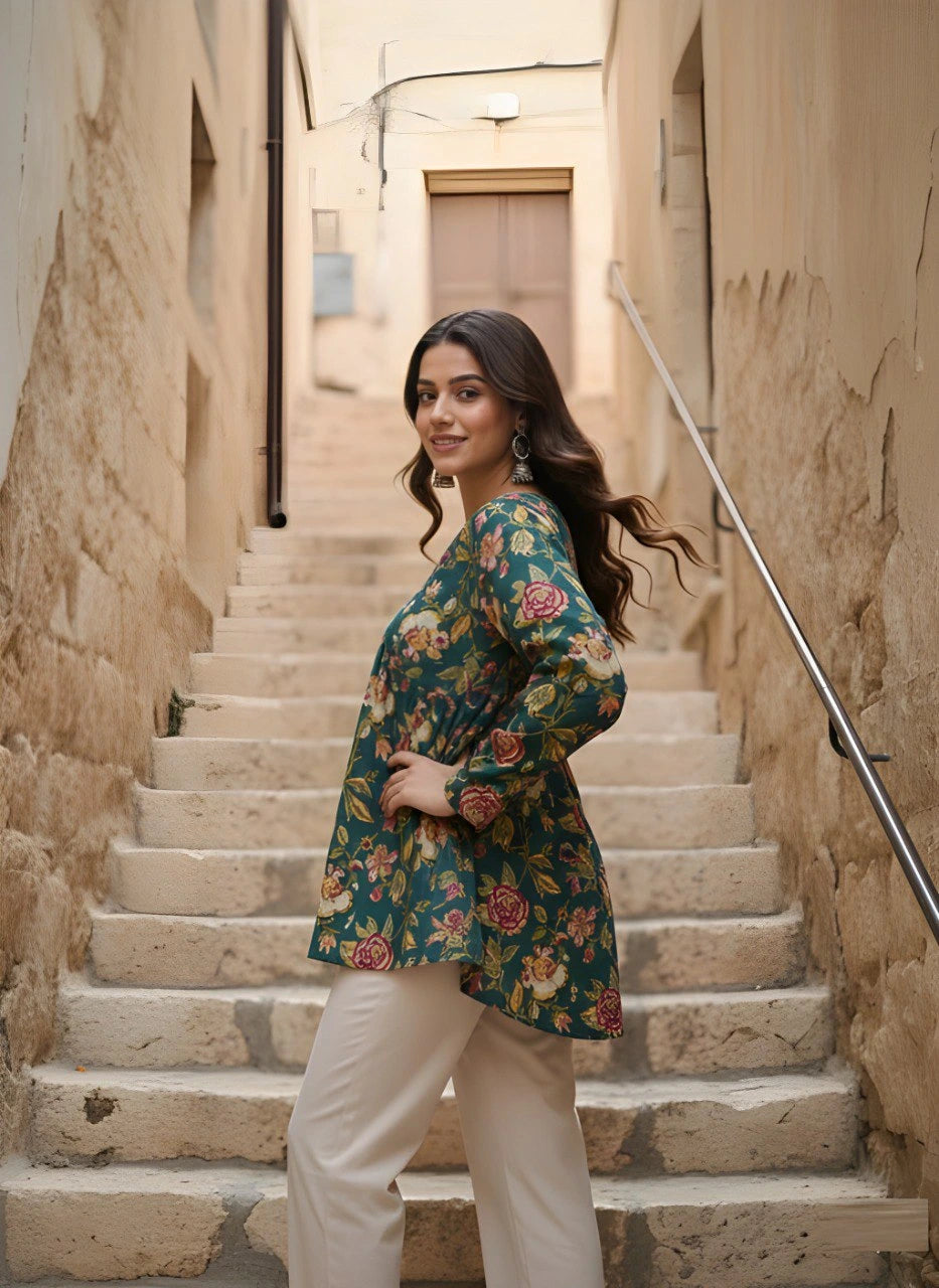 Woman in a floral top and white pants standing on stone steps in an alleyway.