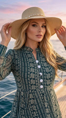 Woman wearing a patterned dress and wide-brimmed hat on a boat with water and sky in the background