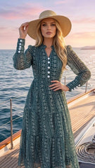 Woman in a long, patterned dress and wide-brimmed hat on a boat with a sunset background