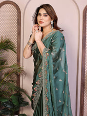 Woman wearing a teal saree with floral patterns indoors