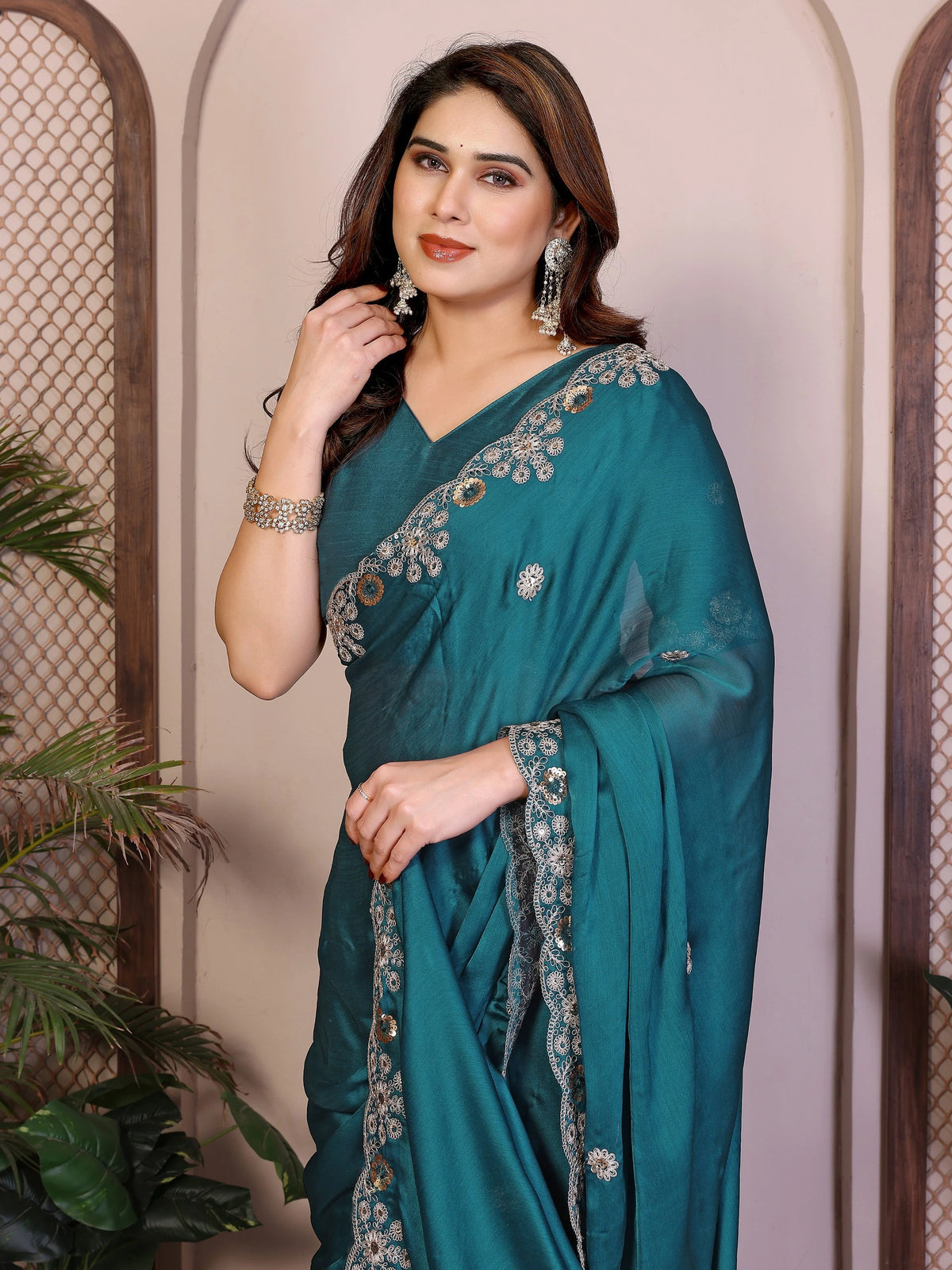 Woman wearing a teal saree with silver embroidery against a neutral background