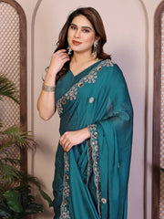 Woman wearing a teal saree with silver embroidery against a neutral background