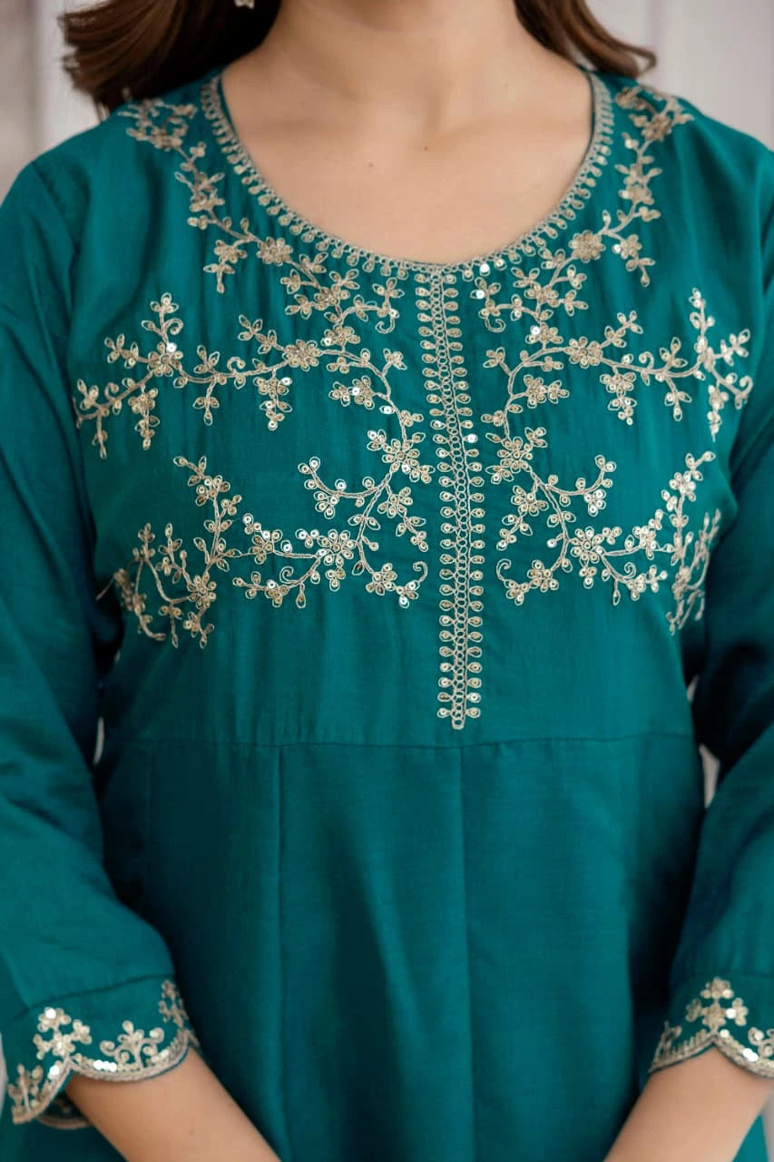 Teal dress with intricate silver embroidery on a plain background
