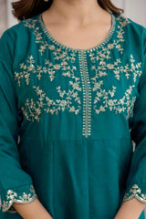 Teal dress with intricate silver embroidery on a plain background