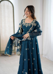 Woman wearing a teal embroidered dress in a minimal indoor setting