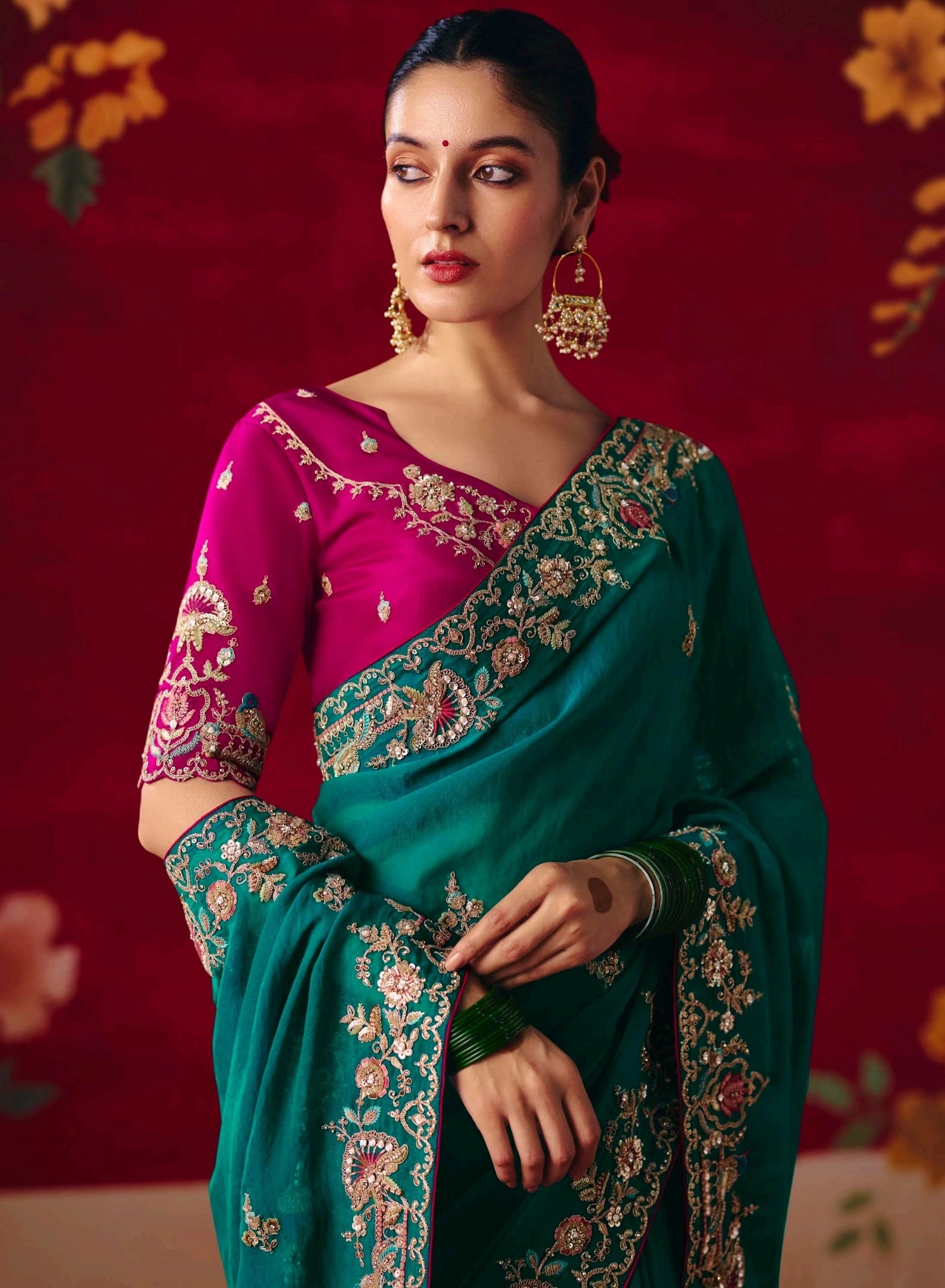 Woman wearing a traditional embroidered saree with a vibrant red background
