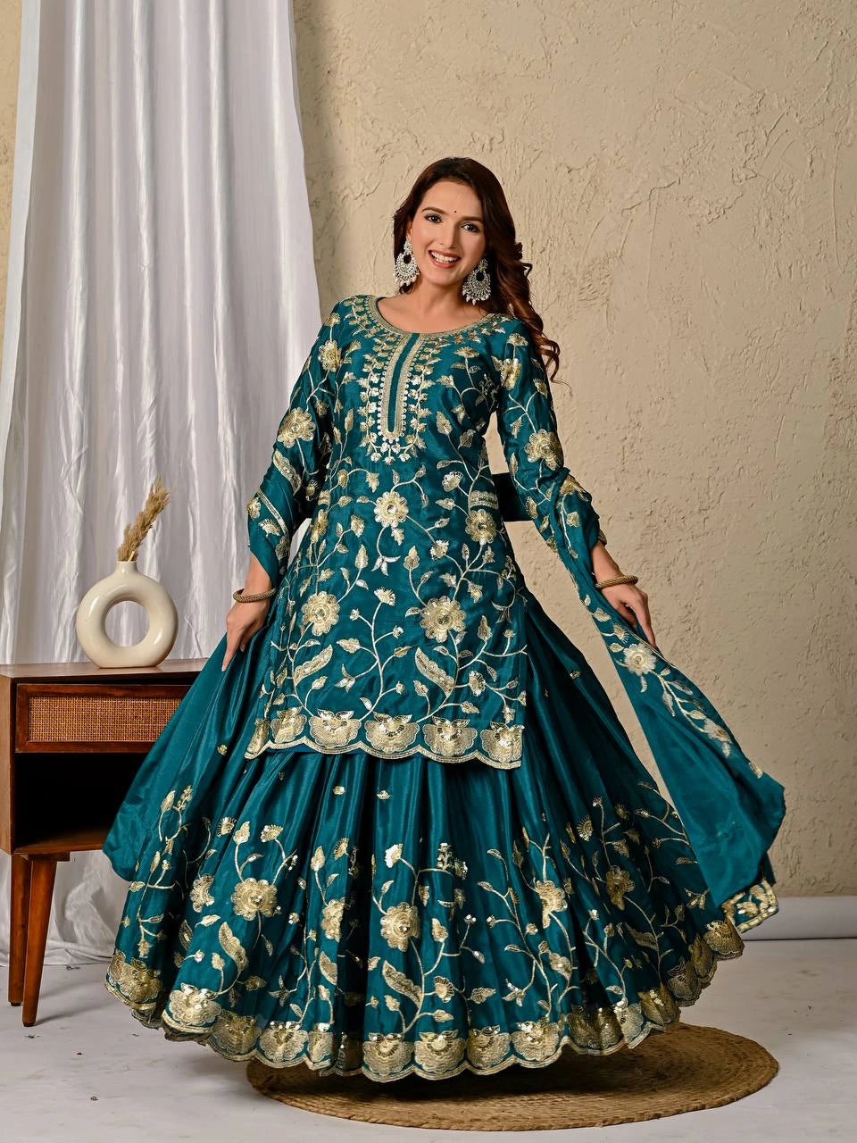 Woman wearing a teal embroidered traditional outfit with a beige background