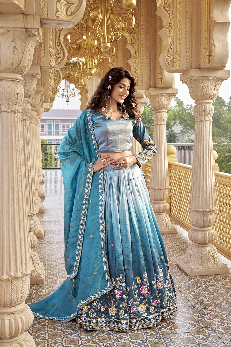Woman in a blue traditional outfit standing in an ornate architectural setting.