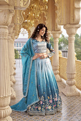 Woman in a blue traditional outfit standing in an ornate architectural setting.