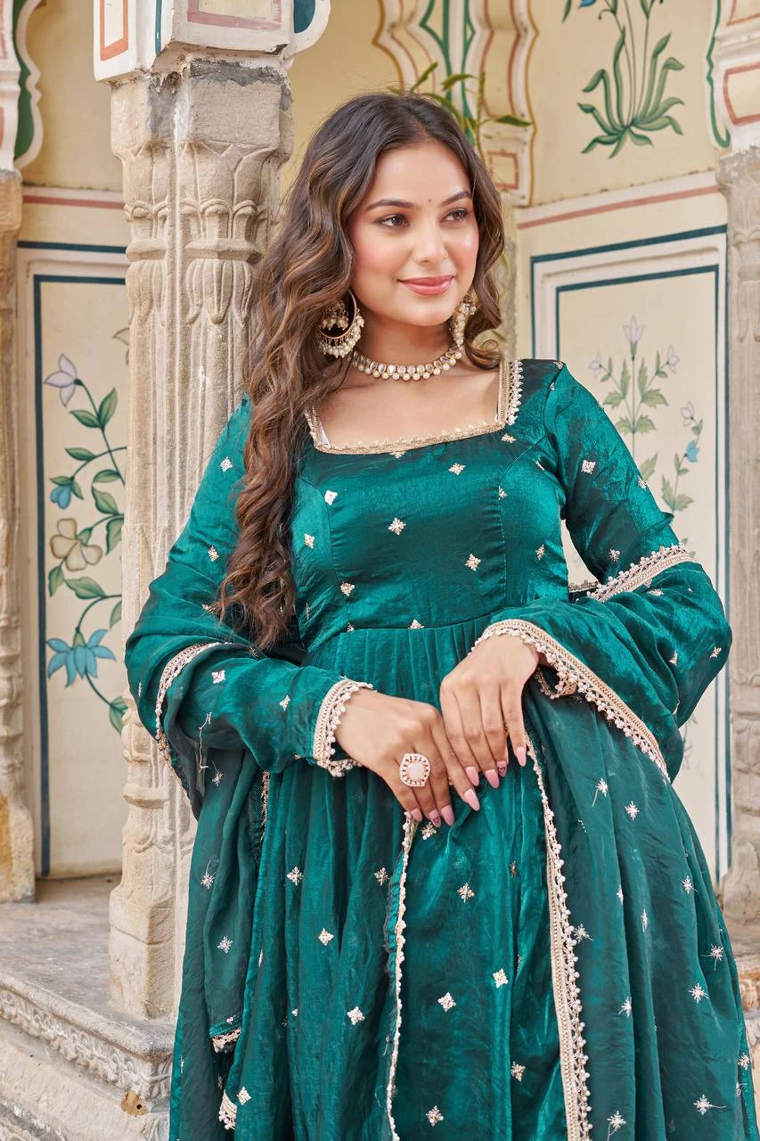 Woman in a teal traditional outfit with floral patterns in an ornate setting