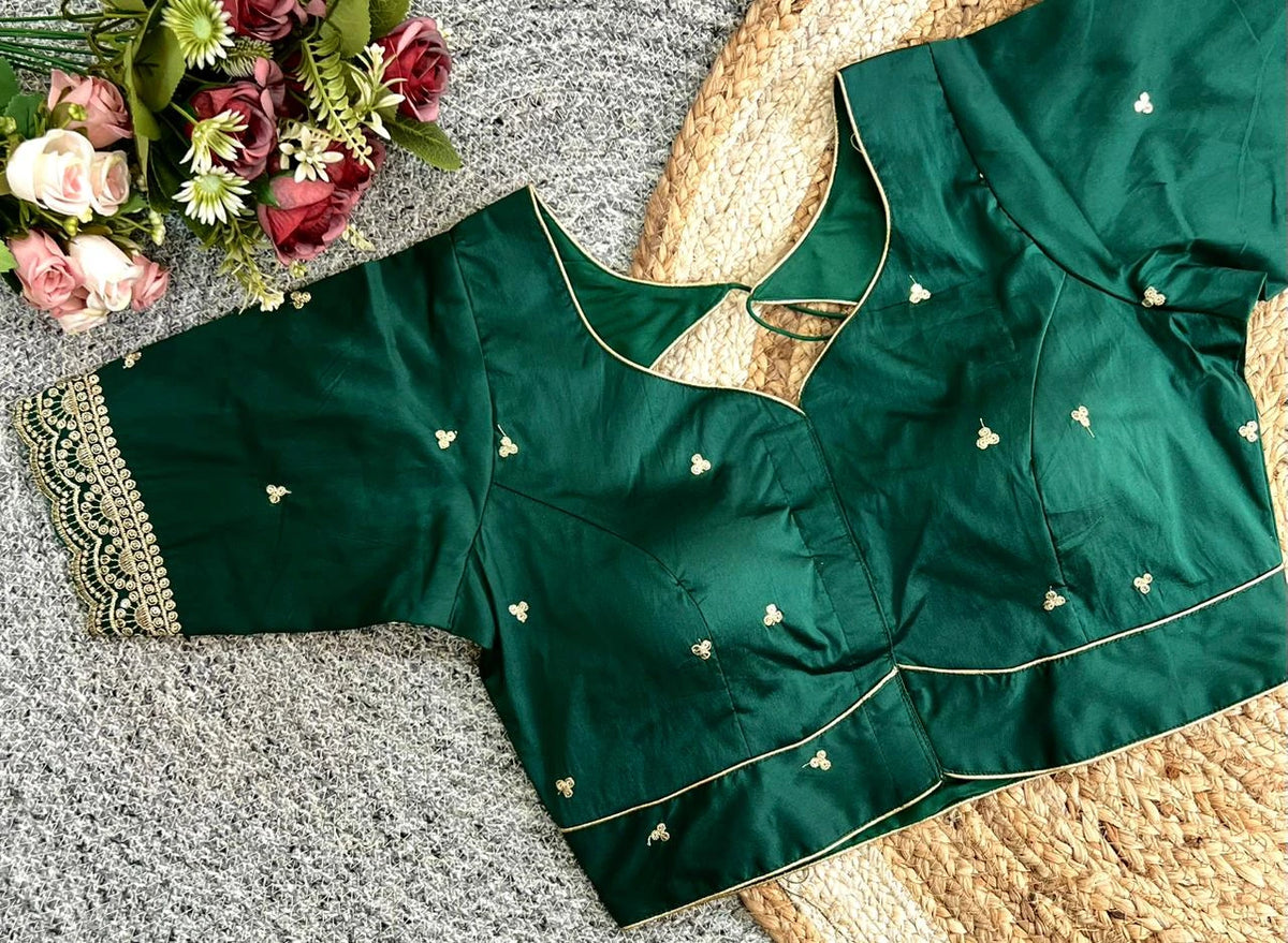 Green blouse with gold embroidery on a textured surface with flowers.