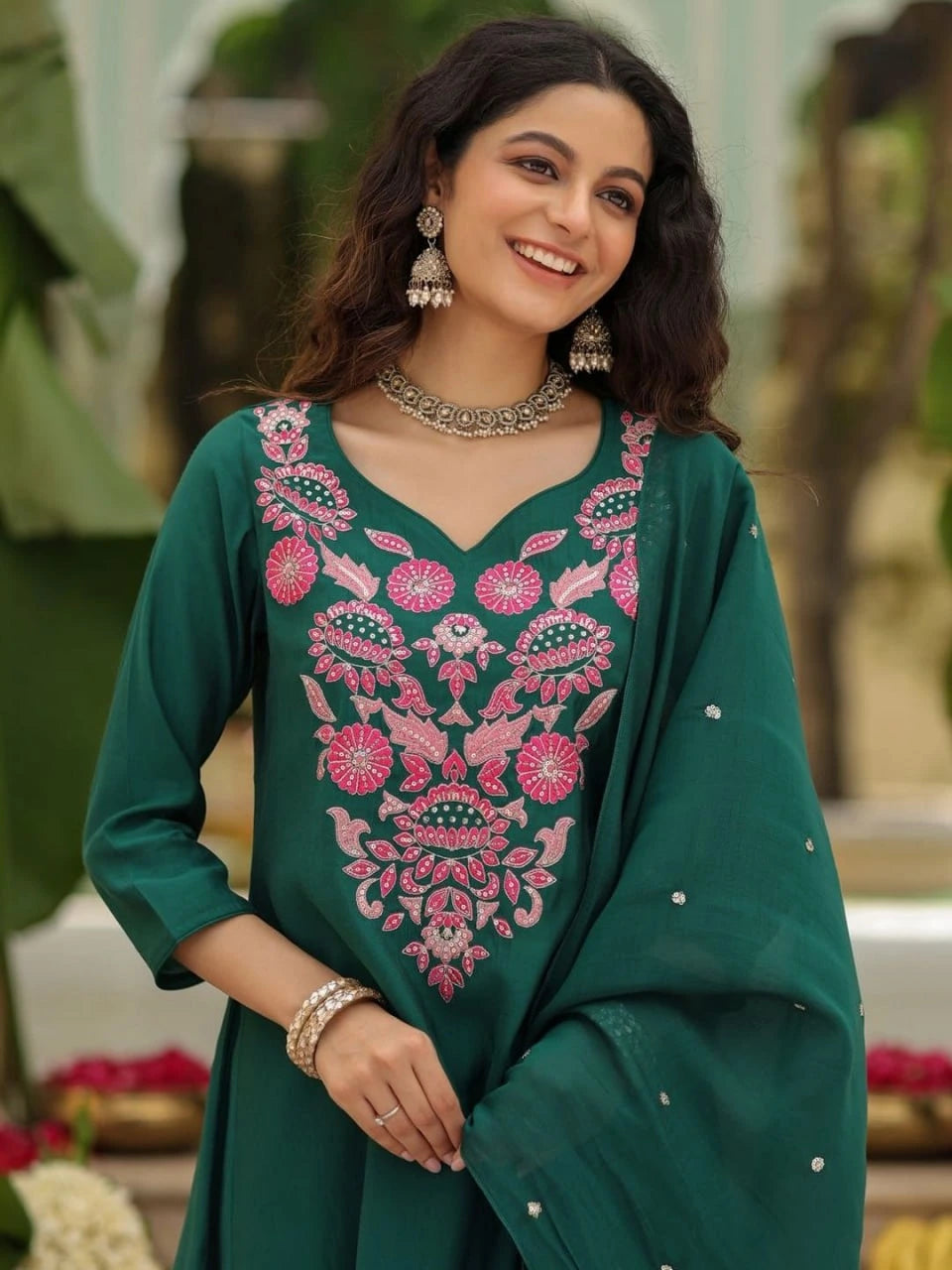 Woman wearing a green embroidered traditional outfit with a blurred outdoor background