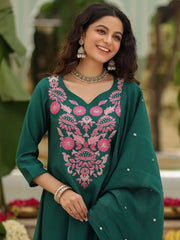Woman wearing a green embroidered traditional outfit with a blurred outdoor background