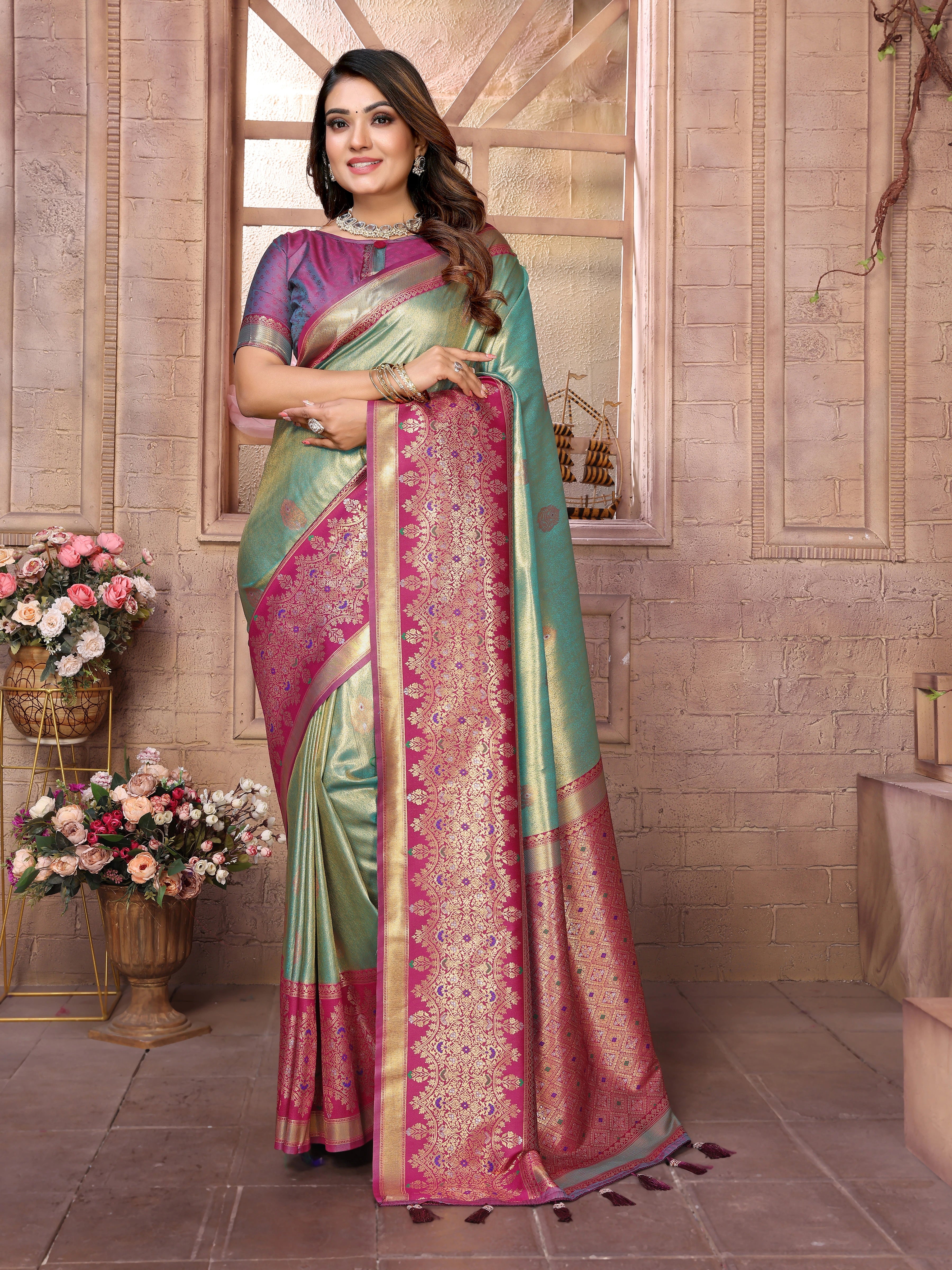 Woman wearing a traditional saree with a decorative border in a room setting.