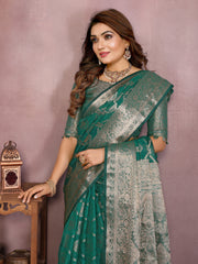 Woman wearing a green saree with a patterned blouse against a pink background