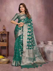 Woman wearing a green saree with a pattern, standing against a neutral background.