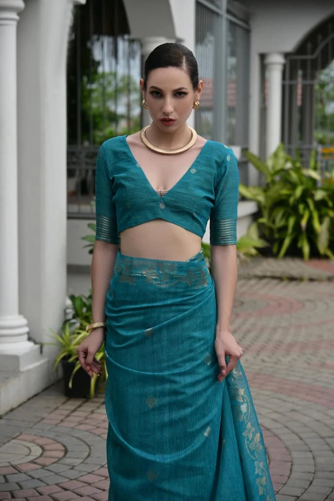 Woman wearing a teal traditional outfit standing outdoors.