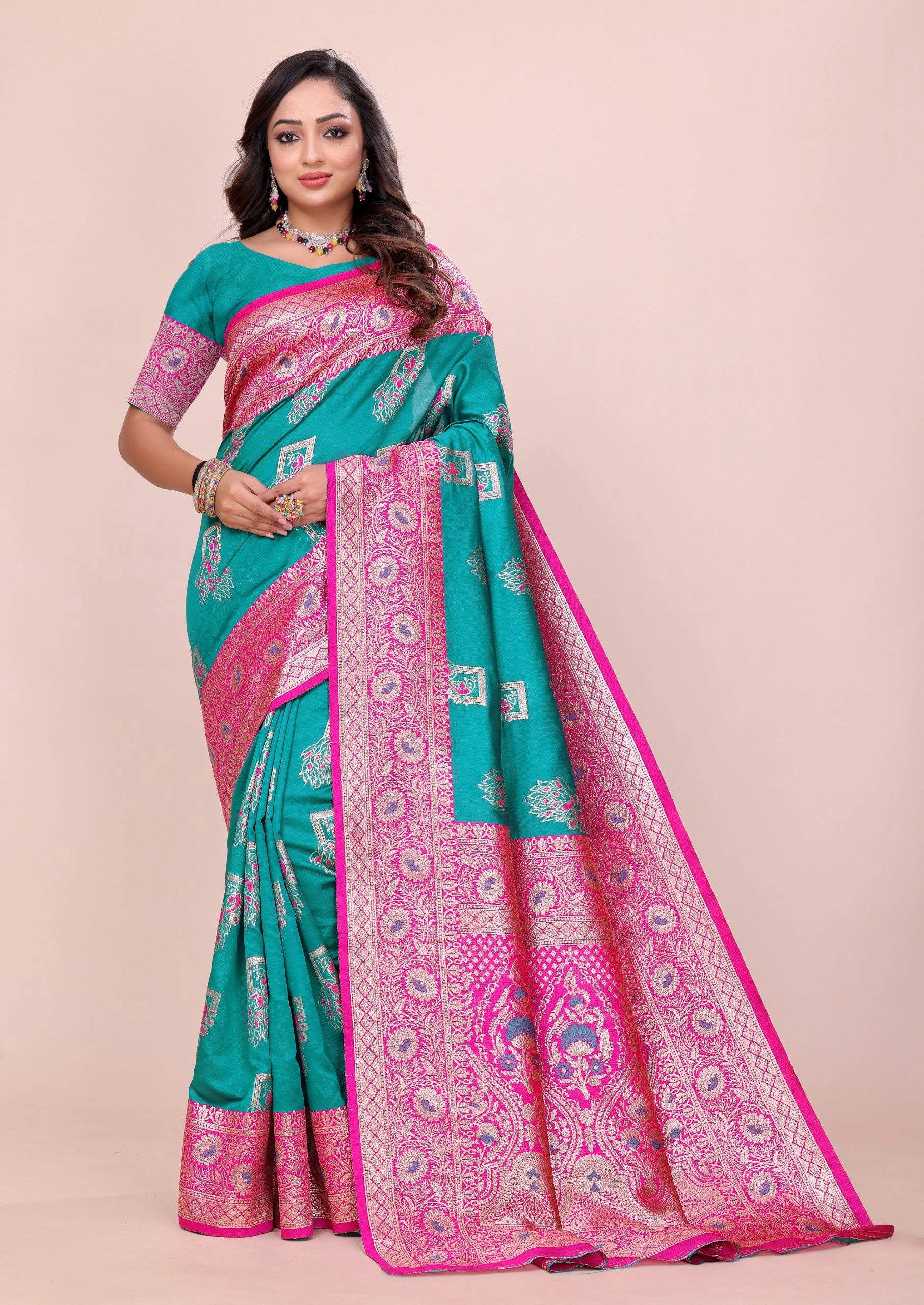 Woman wearing a teal and pink saree with a beige background