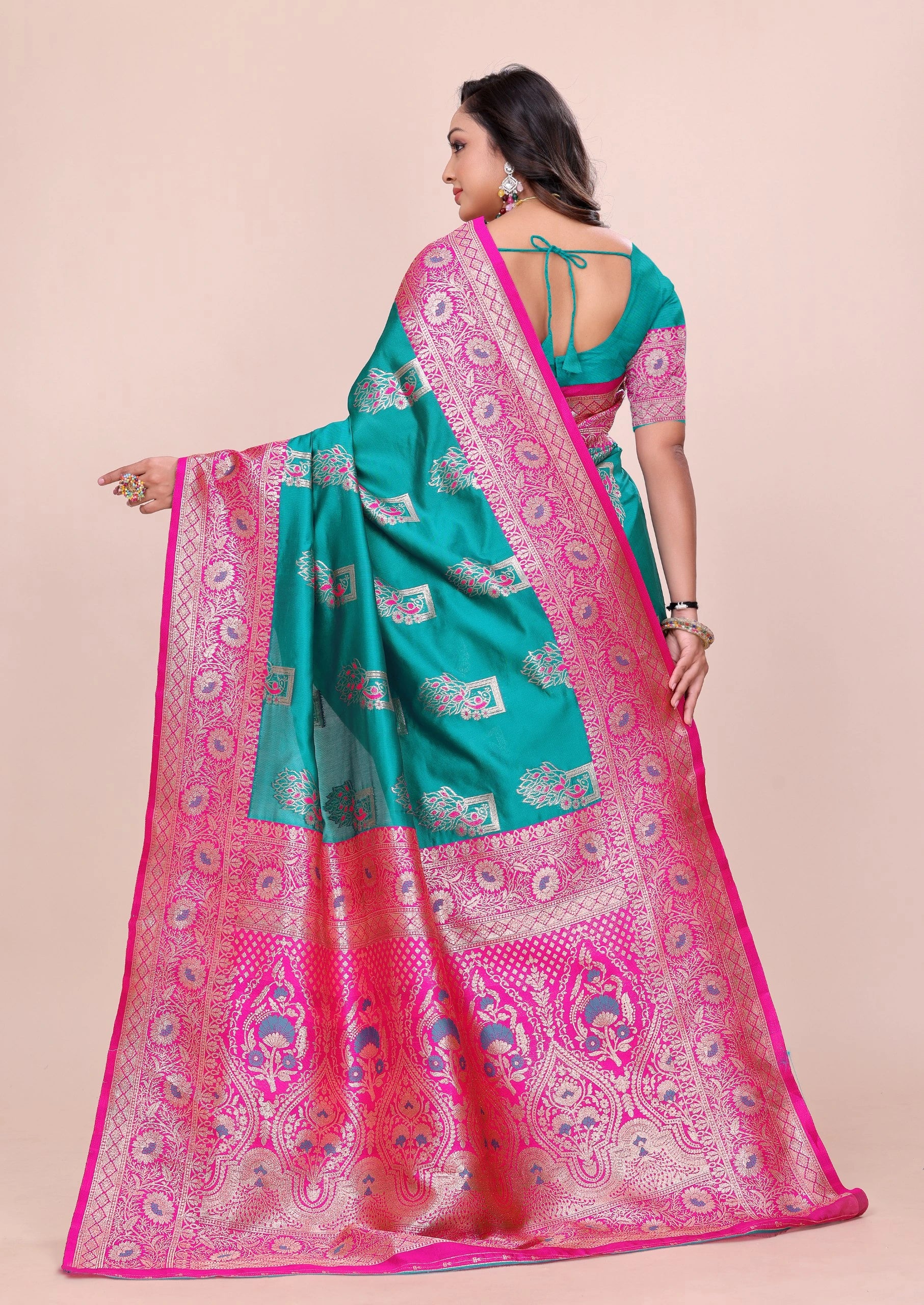 Woman wearing a green and pink saree with a beige background