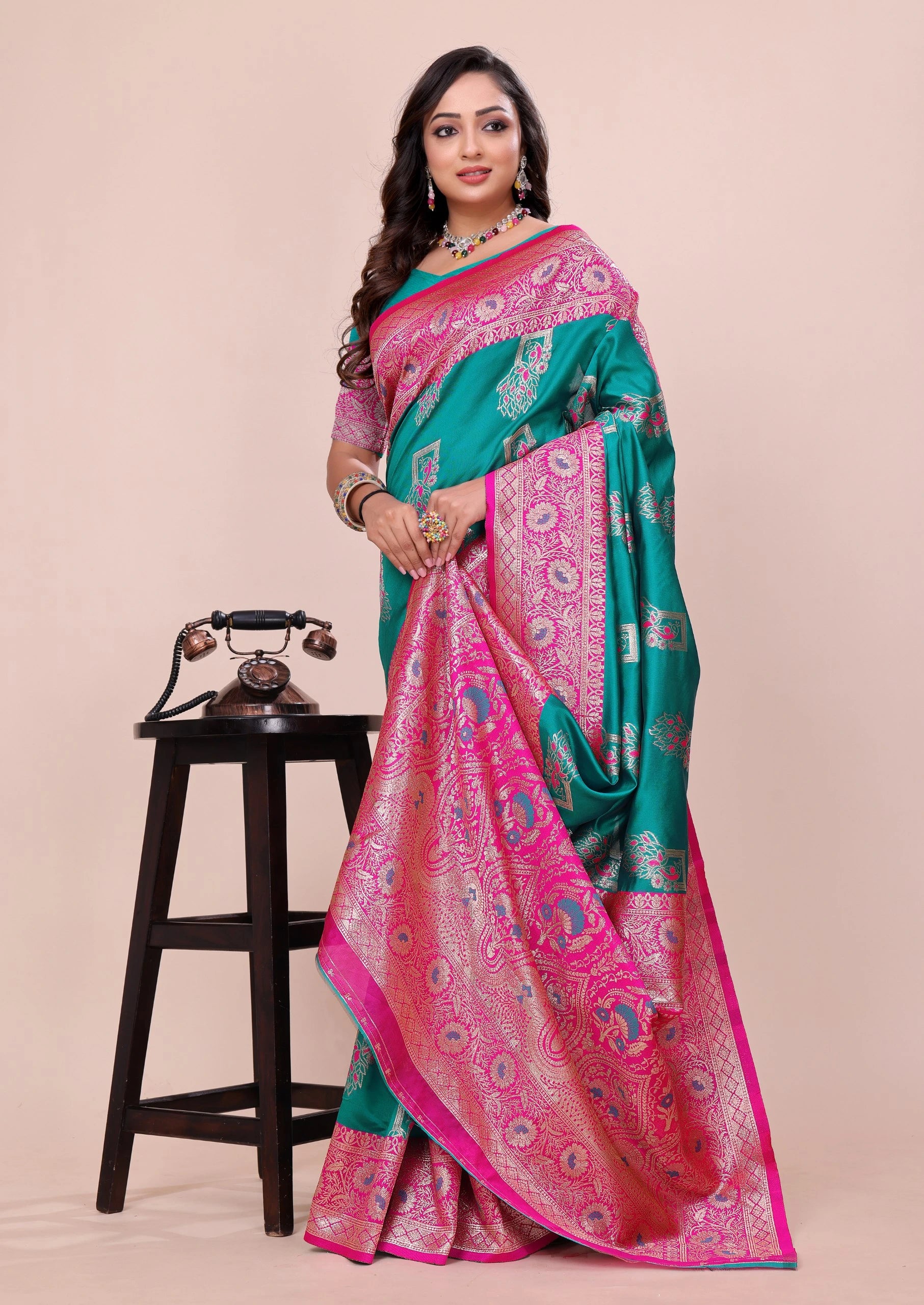 Woman wearing a green and pink saree with a beige background