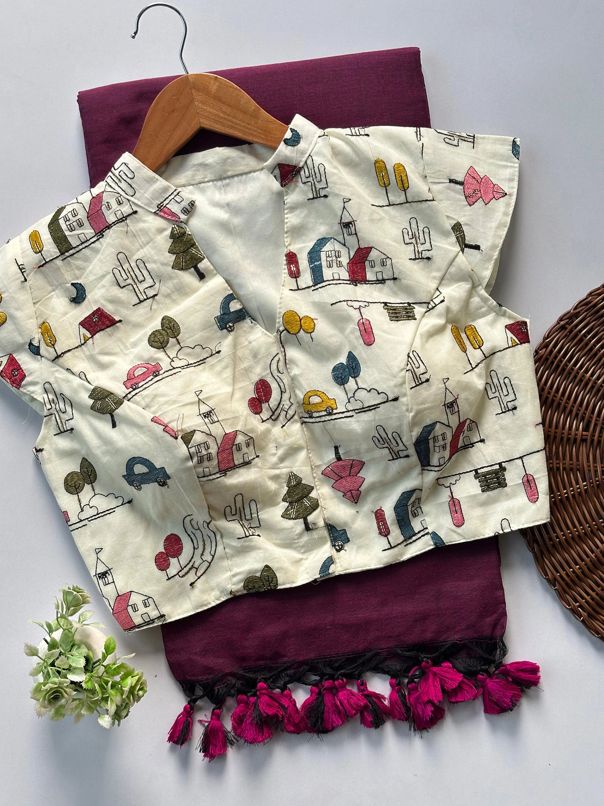 Children's outfit with patterned top and maroon skirt on a white background