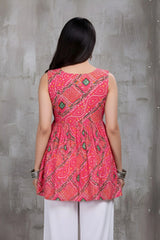 Woman wearing a red patterned top against a gray concrete wall