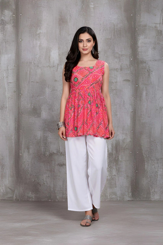 Woman wearing a pink patterned top and white pants against a gray background