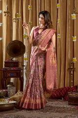 Woman in a pink saree standing in a decorated room with vintage decor.