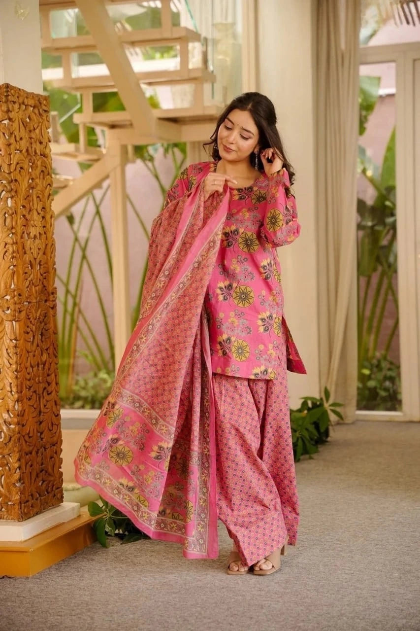 Woman in a pink traditional outfit standing in a decorated indoor setting.